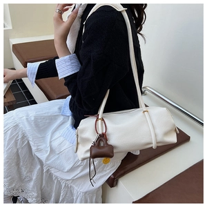 Detail showing white leather Boston bag texture with small brown charm accessory