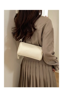Detail of lychee textured cream shoulder bag worn under the arm by a model