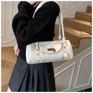 Detail of white leather baguette bag with heart pendant and metallic stud accents