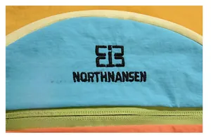 Detailed macro view of waterproof nylon fabric with colorful stitching and EiB logo embroidery