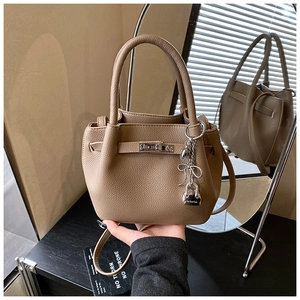 Detail of khaki leather tote with silver metal buckle and elegant bow charm accent