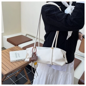 White minimal leather shoulder bag with a brown decorative charm pouch accessory