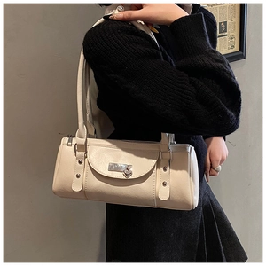 Close-up of minimalist cream leather baguette bag with silver hardware and shoulder strap