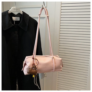 Close-up of pink pebbled leather Boston bag with round silhouette and brown mini charm