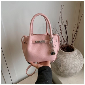 Detail of pink lychee leather handbag featuring silver metal clasp and sweet heart charm