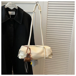 Close-up of cream Boston bag with lychee texture and trendy decorative mini charm pendant