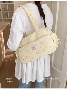 Detail of cream star pattern shoulder bag with side drawstring and adjustable strap