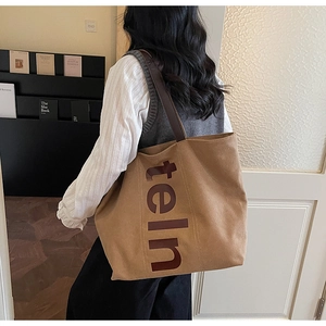 Détail du sac cabas en toile beige avec imprimé teln sur un mannequin en intérieur