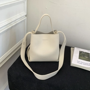 Detail of off-white lychee grain leather bucket bag with top handle and wide shoulder strap