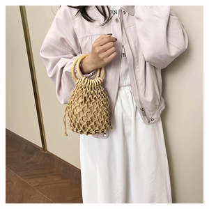 Détail du sac seau en paille tissé main avec anses en bois et motif bohème en maille