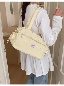 Detail of a beige nylon shoulder bag with silver star patterns and adjustable drawstring sides