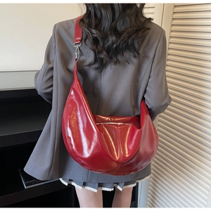 Detail of adjustable strap and silver zipper on the red high-shine hobo shoulder bag