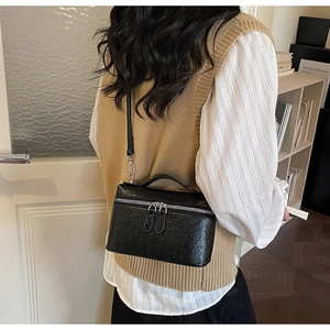 Close-up of black ostrich pattern leather square bag with silver double zipper detail