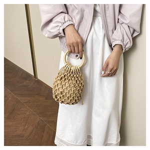 Détail du sac seau en paille tissé main avec poignée en bois et texture en maille