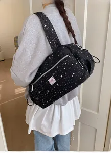 Detail of black canvas star print tote bag with pink bow patch and side drawstring pocket