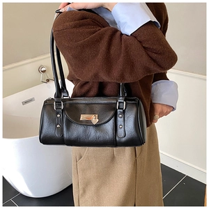 Detail of the black leather Boston bag with silver hardware and a gold heart pendant