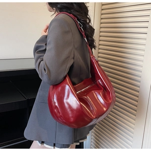 Detailed close-up of glossy deep red hobo bag with adjustable silver metal buckle