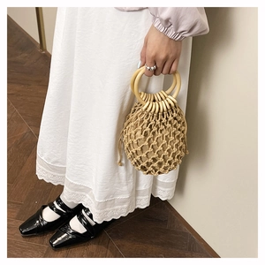 Détail du sac seau en paille tressée avec grande poignée en bois et doublure à cordon