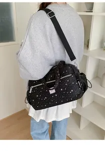 Detail of black canvas crossbody bag with white star pattern and adjustable strap