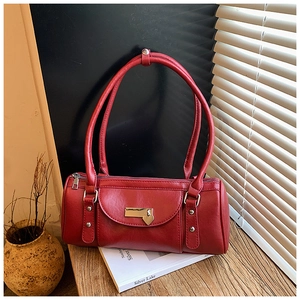Close-up of red cylindrical shoulder bag with heart pendant and gold metallic hardware