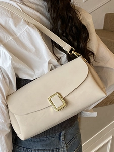 Sac bandoulière beige minimaliste avec boucle dorée porté par un mannequin de mode