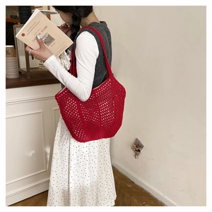 Detailed close-up of a red crochet tote bag with intricate hollowed-out knit patterns