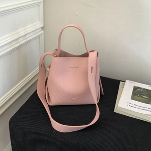 Close-up of pink bucket bag with litchi grain texture and elegant wide shoulder strap