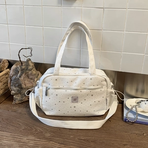 Close-up of white star pattern shoulder bag with side drawstring and silver print