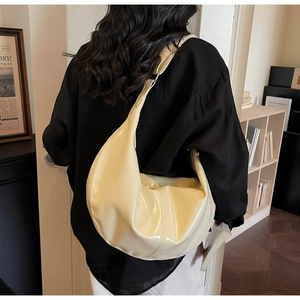 Detail of cream yellow patent leather hobo bag with reflective finish and wide shoulder strap