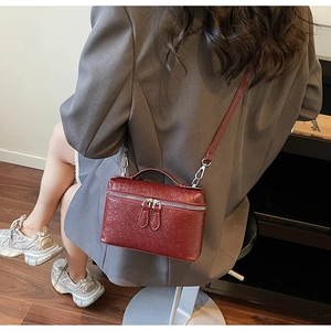 Close-up of wine red ostrich texture leather square box bag with dual metal zippers