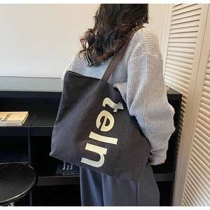 Détail d'un grand sac fourre-tout en toile gris foncé avec lettrage blanc et anses en cuir