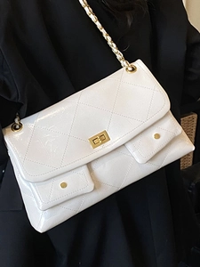 White glossy quilted tote bag with gold chain strap and dual pockets worn by model