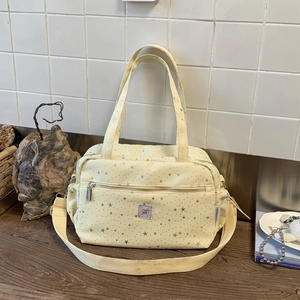 Detail of light yellow star-printed tote bag with front pocket and adjustable strap