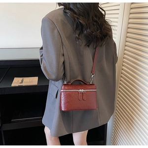 Detailed view of the red ostrich-embossed leather mini box bag with silver hardware detail