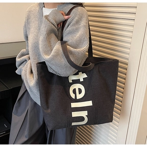Vue détaillée du sac cabas en toile noire avec imprimé lettres et bandoulière large