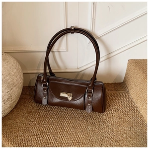 Close-up of vintage brown leather cylinder bag with silver heart pendant on textured stairs