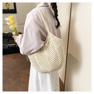 Detail shot of hand-woven hollow crochet tote bag in beige cotton rope for summer beach use
