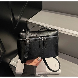 Detail of black ostrich embossed crossbody box bag with dual zippers and handle