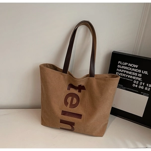 Détail du grand sac cabas en toile avec lettrage 'teln' marron et poignées en cuir