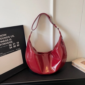 Detailed close-up of dark red patent leather hobo bag with pleated texture and silver hardware