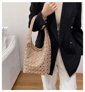 Detail of beige punk underarm bag with silver studs on leather shown on model
