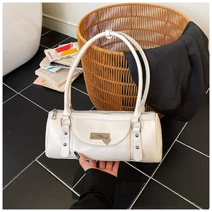 Close-up of cream cylindrical shoulder bag with heart pendant and silver hardware