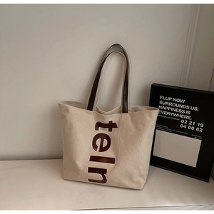 Gros plan d'un grand sac cabas en toile avec lettres marron et poignées en cuir