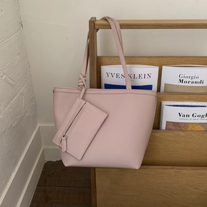 Close-up of pink leather tote bag featuring a knotted strap and a small coin purse