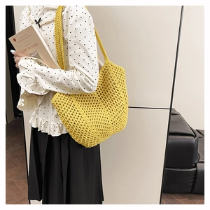 Close-up of bright yellow crochet tote bag showing hollow-out knit texture and long strap