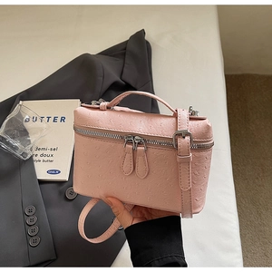 Detailed view of a pink ostrich texture box bag with metal zipper and leather handle