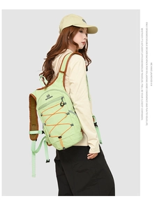 Model wearing a light green nylon backpack with orange elastic drawstrings for outdoor travel