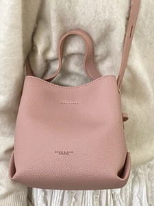 Chic pink bucket bag with lychee texture held by a person in white pleated skirt
