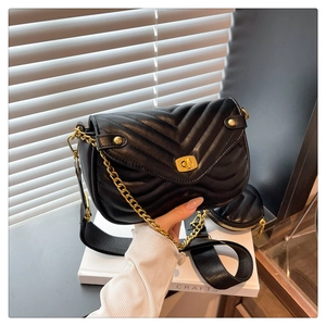 Detail of black chevron quilted shoulder bag with gold chain and heart coin purse