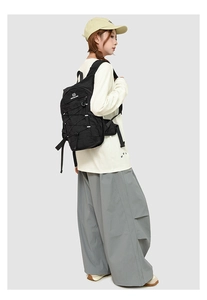 Detail of black outdoor backpack with criss-cross drawstring and reinforced buckles